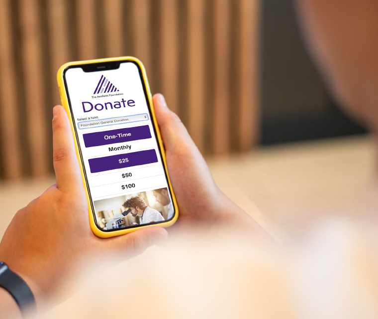 Person holding phone showing The Aesthetic Foundation donation page
